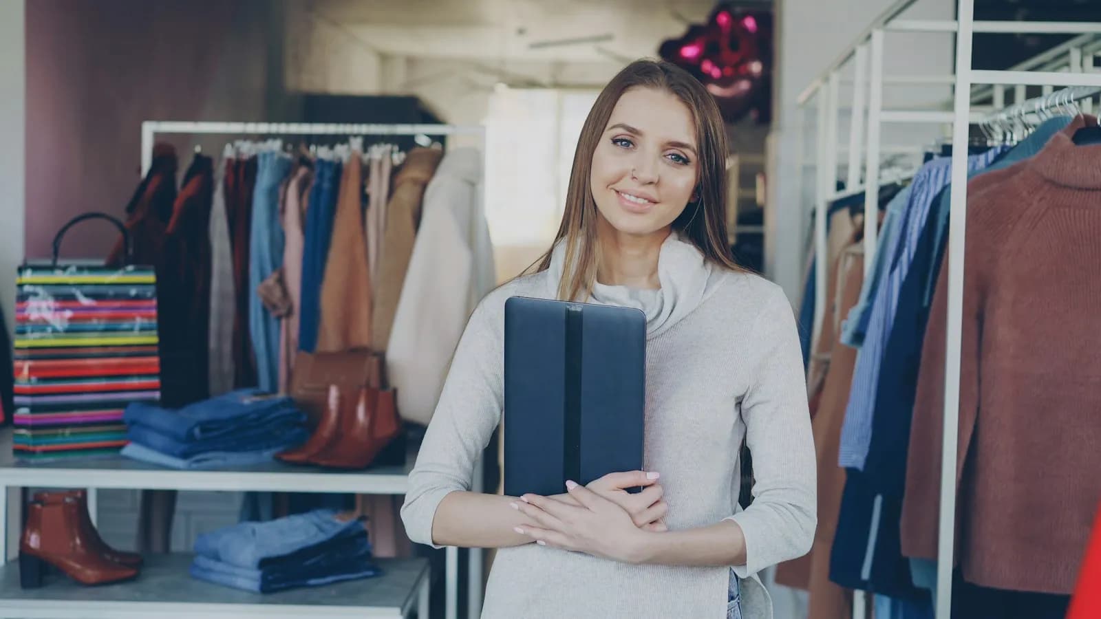 Dueña de una tienda de ropa sonriendo con una tablet en la mano