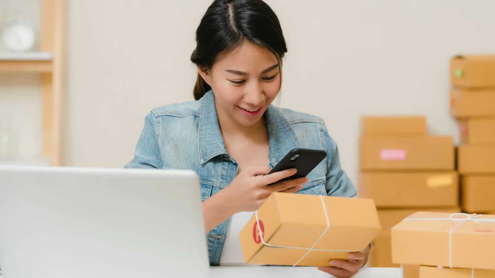 Emprendedora preparando pedidos de su tienda online junto a una notebook